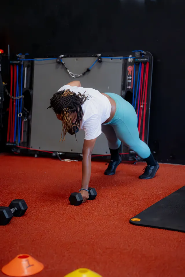 Woman doing a plank row with a dumbbell during a coached session