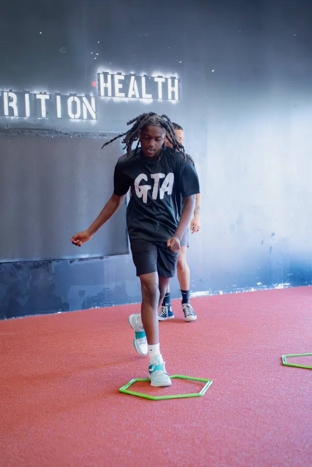 Athlete working footwork through an agility hex in front of the Grind Time wall